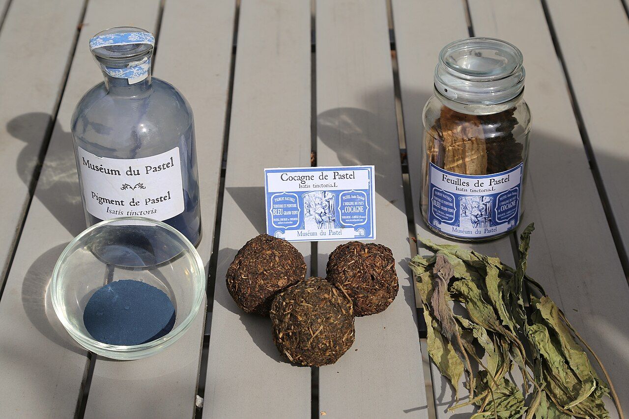 Three stages of botanical dye production: woad leaves, balls made from crushed leaves, and blue pigment