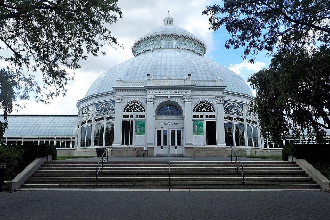 The Enid A. Haupt Conservatory at the New York Botanical Garden, its white iron-and-glass arches leading toward the central dome